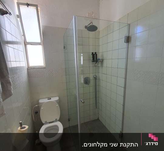 מקלחון זכוכית עם ראש מקלחת ומדף סבונים